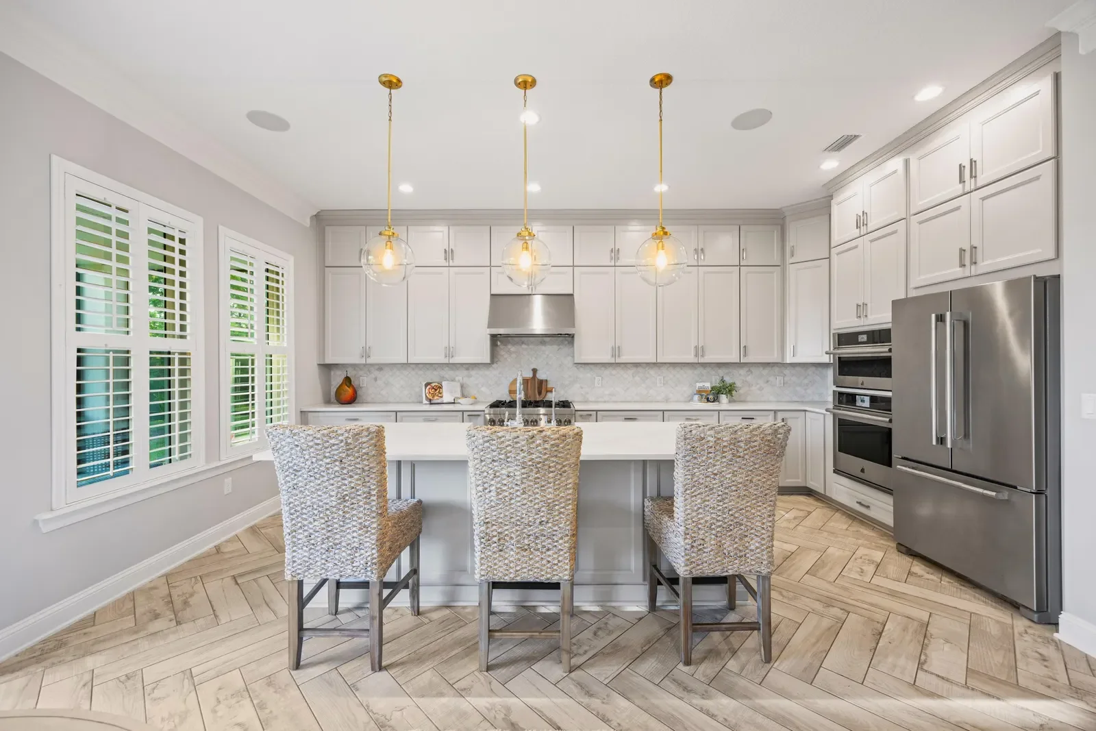 Bright kitchen with brass pendants and herringbone floors in Jacksonville, FL. Real estate photography by Megapixeler