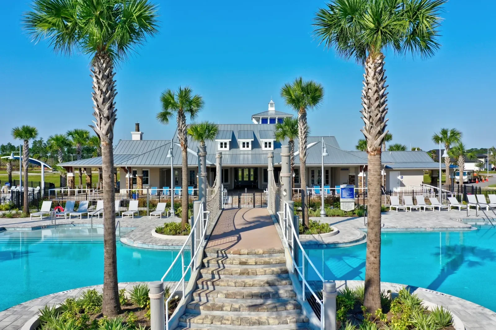 Community pool and clubhouse with footbridge in North Florida. Community amenity photography by Megapixeler