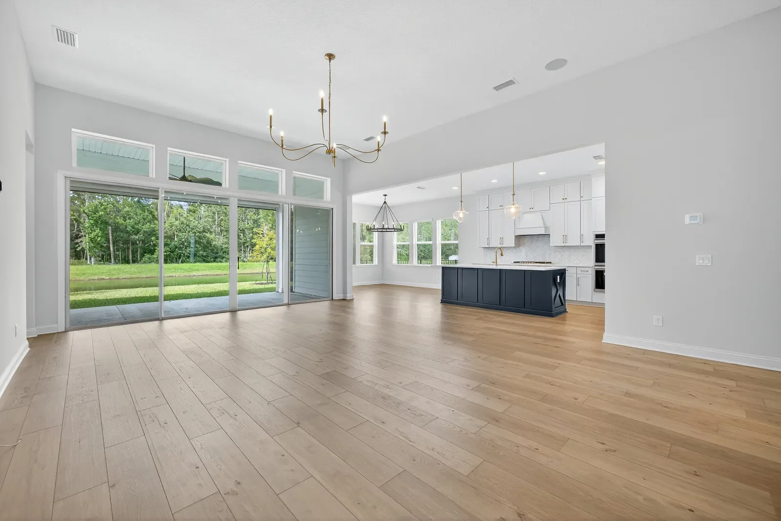 Empty family room open to the kitchen before virtual staging in North Florida. Real estate photography by Megapixeler