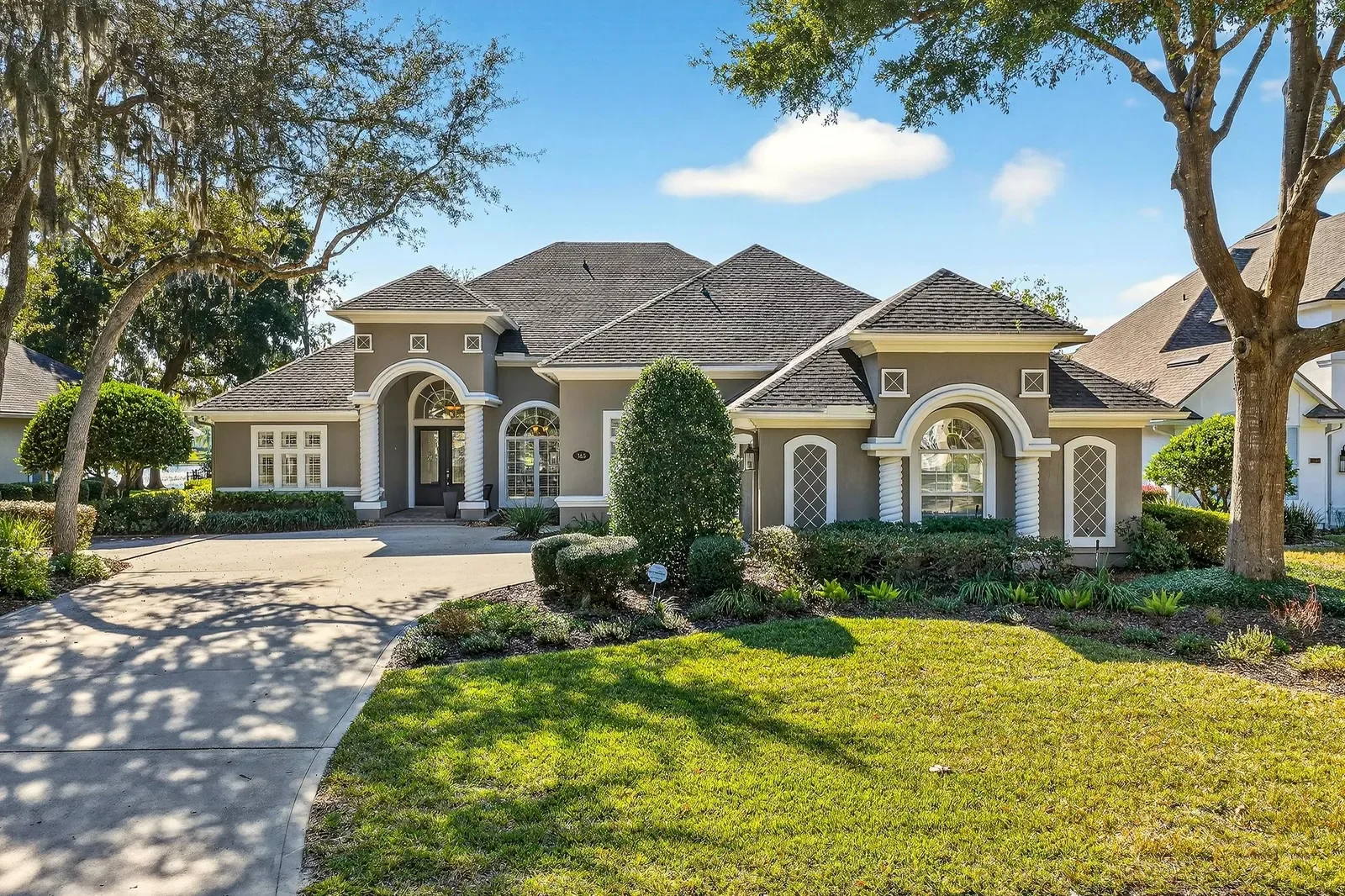 Estate home with arched entry under live oaks in St. Johns, FL. Real estate photography by Megapixeler