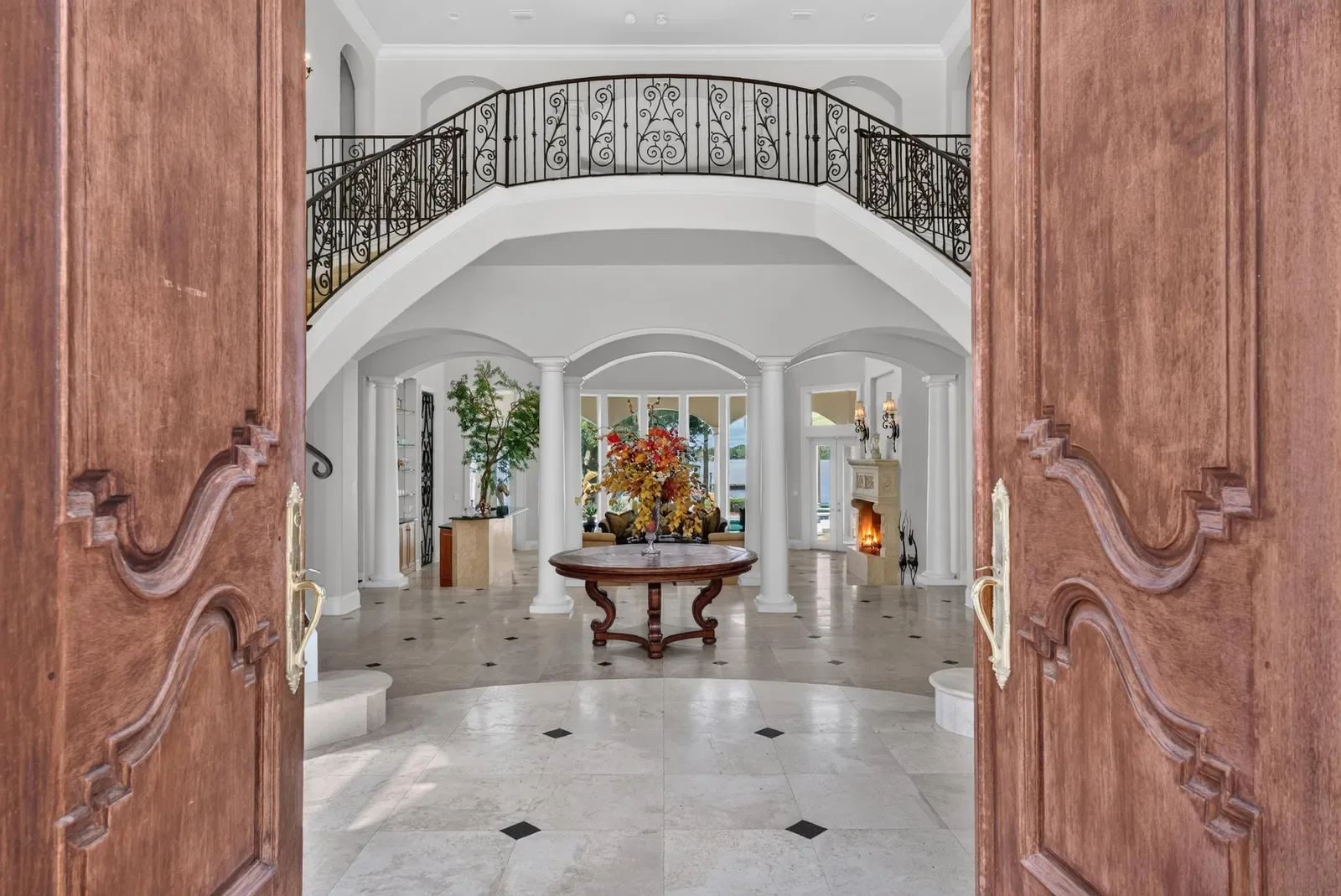 Grand arched entrance with carved double doors in Jacksonville, FL. Real estate photography by Megapixeler