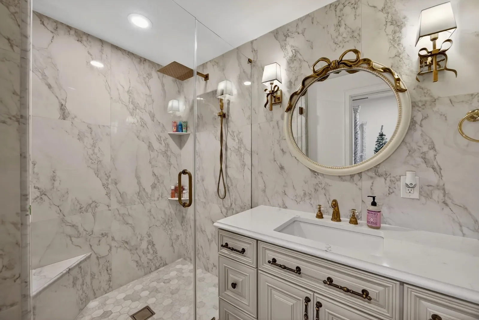 Marble bath with brass fixtures and round mirror in Jacksonville, FL. Real estate photography by Megapixeler
