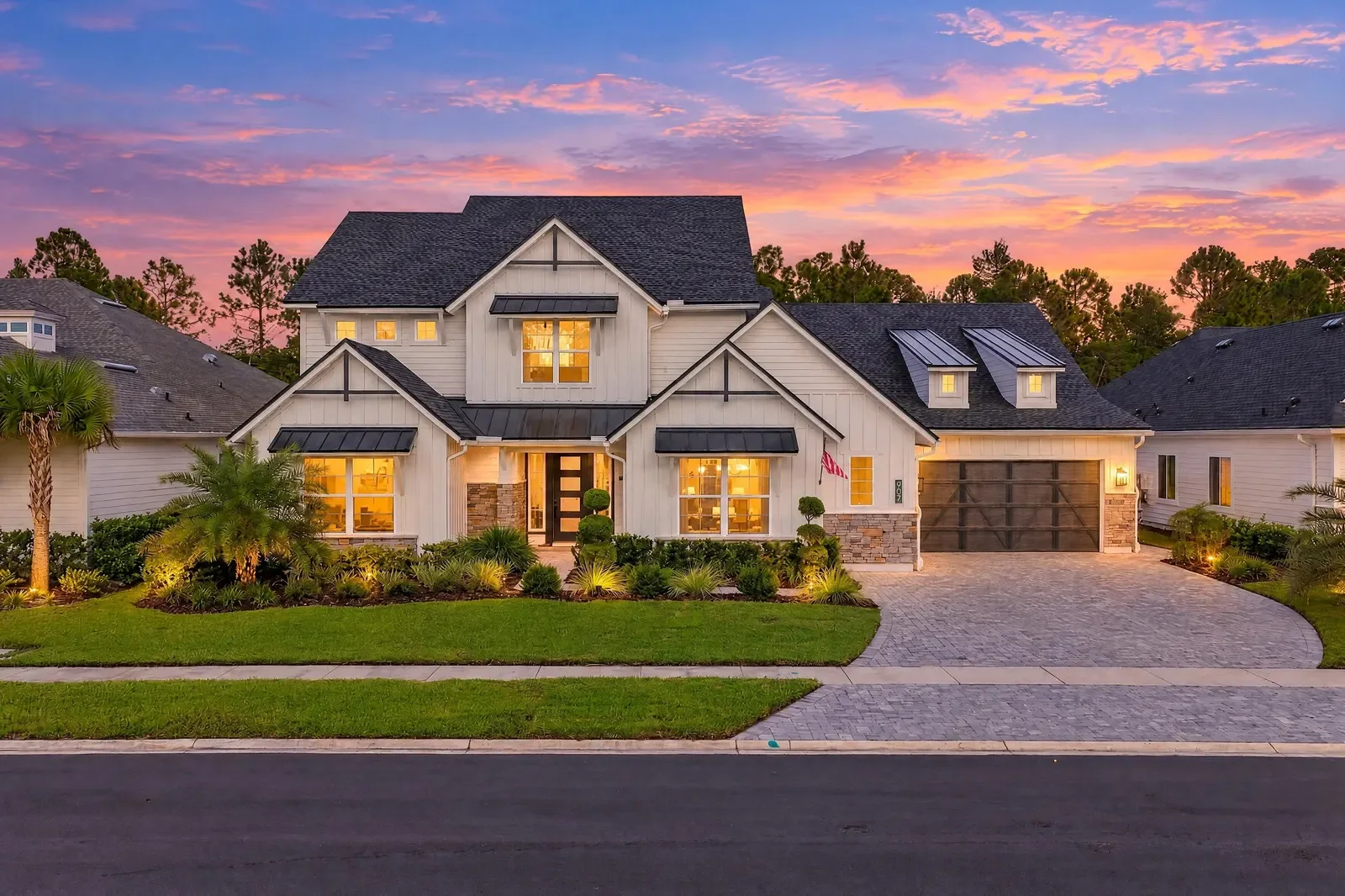 Modern farmhouse at dusk with glowing windows and landscape lighting in Ponte Vedra Beach, FL. Twilight photography by Megapixeler