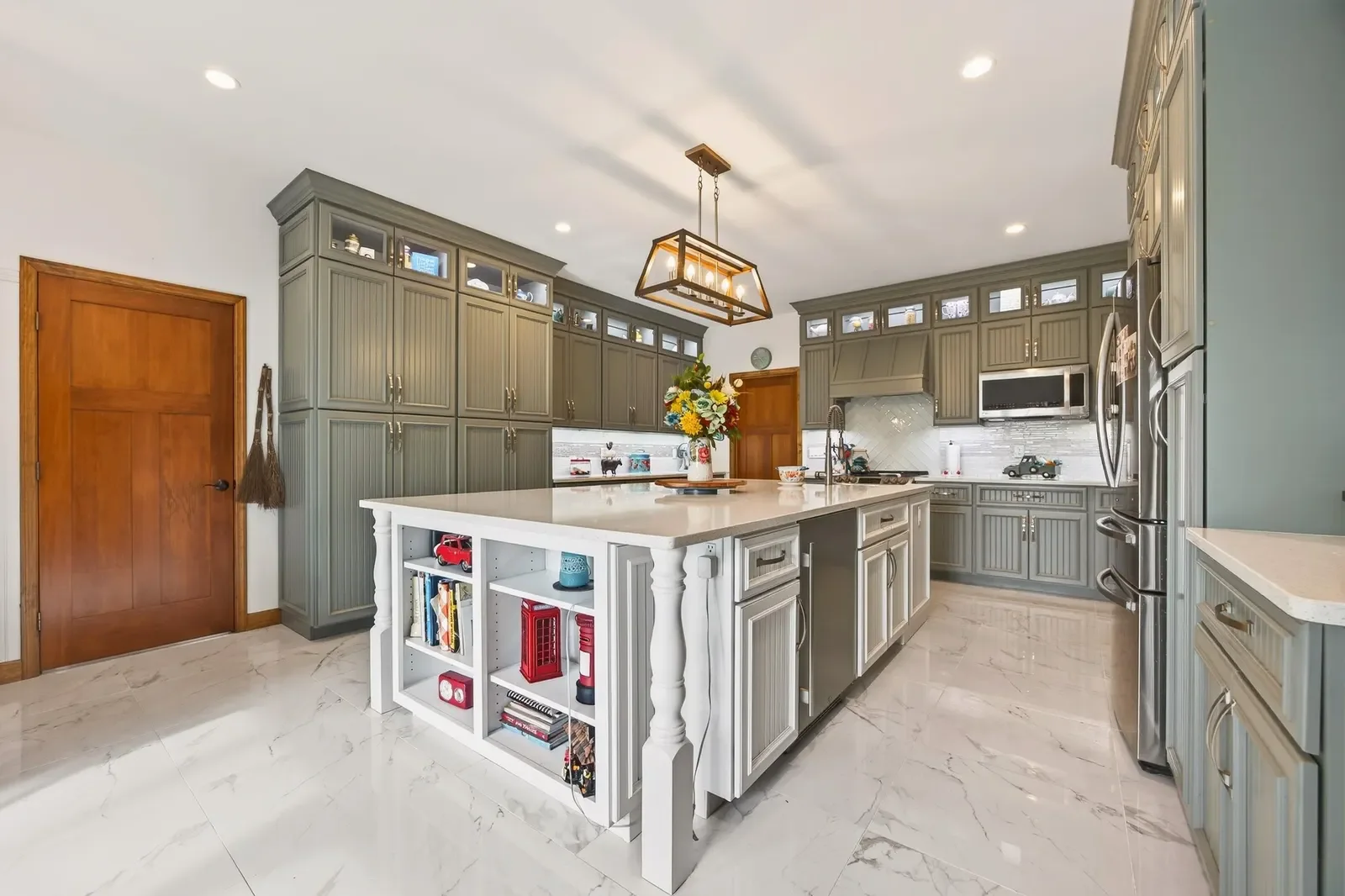 Sage green custom kitchen with marble island and lantern pendant, Pomona Park lake estate in North Florida. Real estate photography by Megapixeler