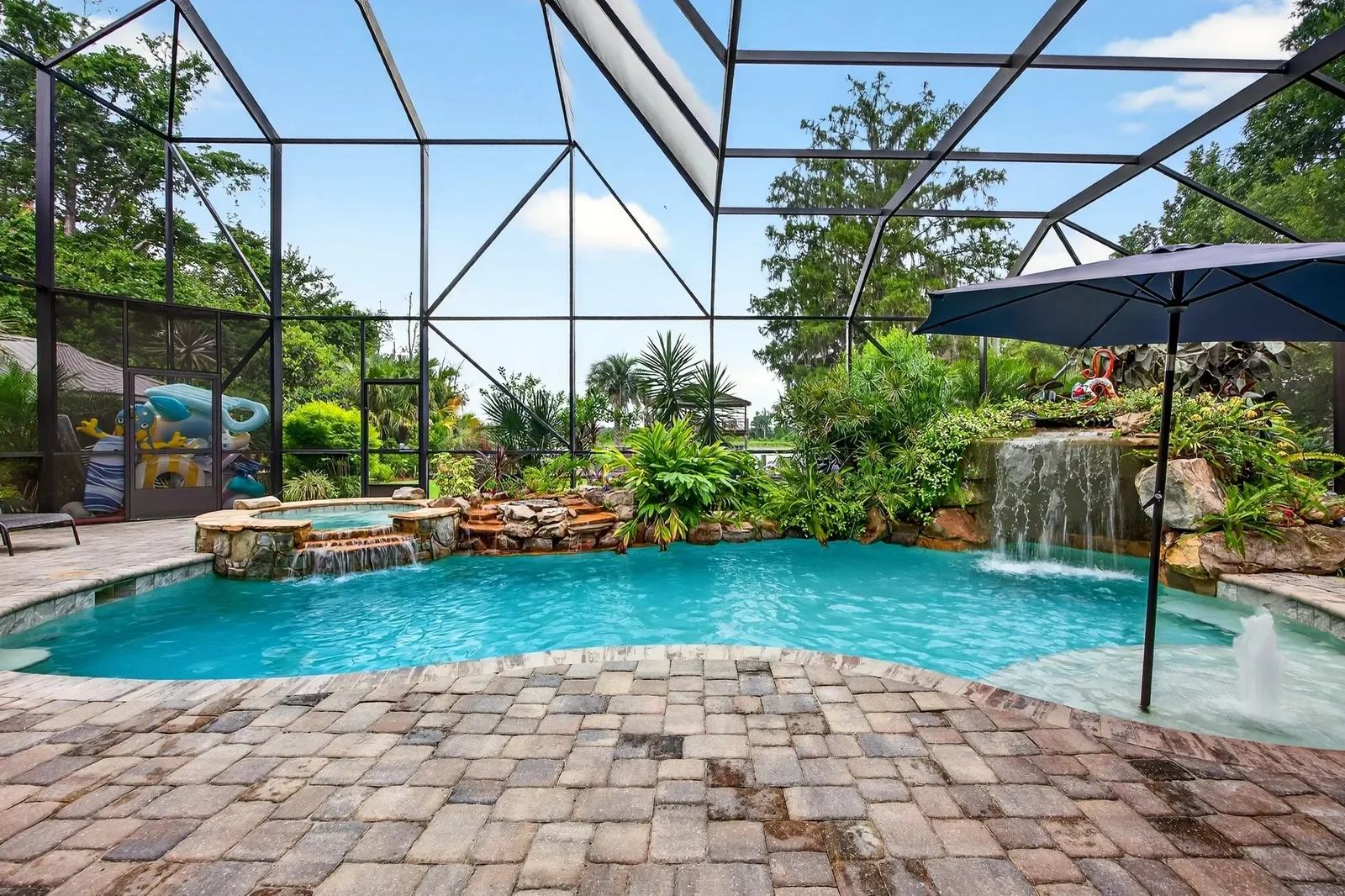 Screened lagoon pool with waterfall and tropical landscaping in Pomona Park, FL. Community amenity photography by Megapixeler