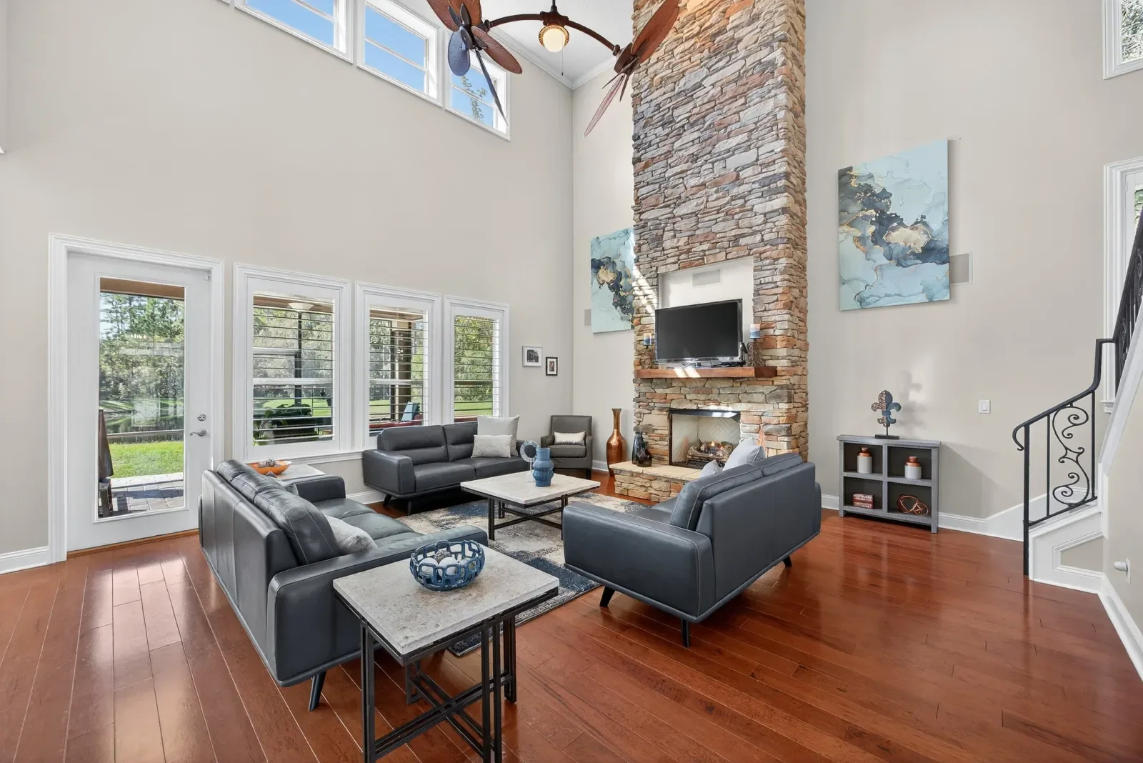 Two-story family room with stacked-stone fireplace in Fruit Cove, FL. Real estate photography by Megapixeler