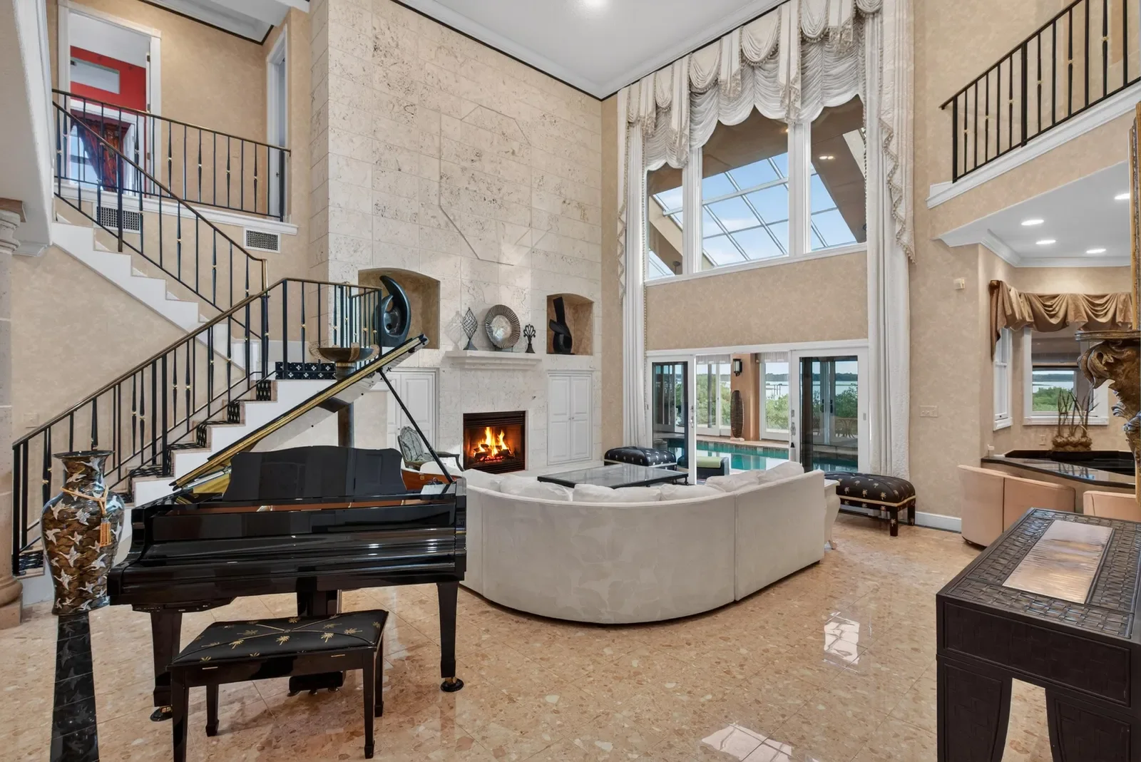 Two-story living room with grand piano and fireplace in St. Augustine, FL. Real estate photography by Megapixeler