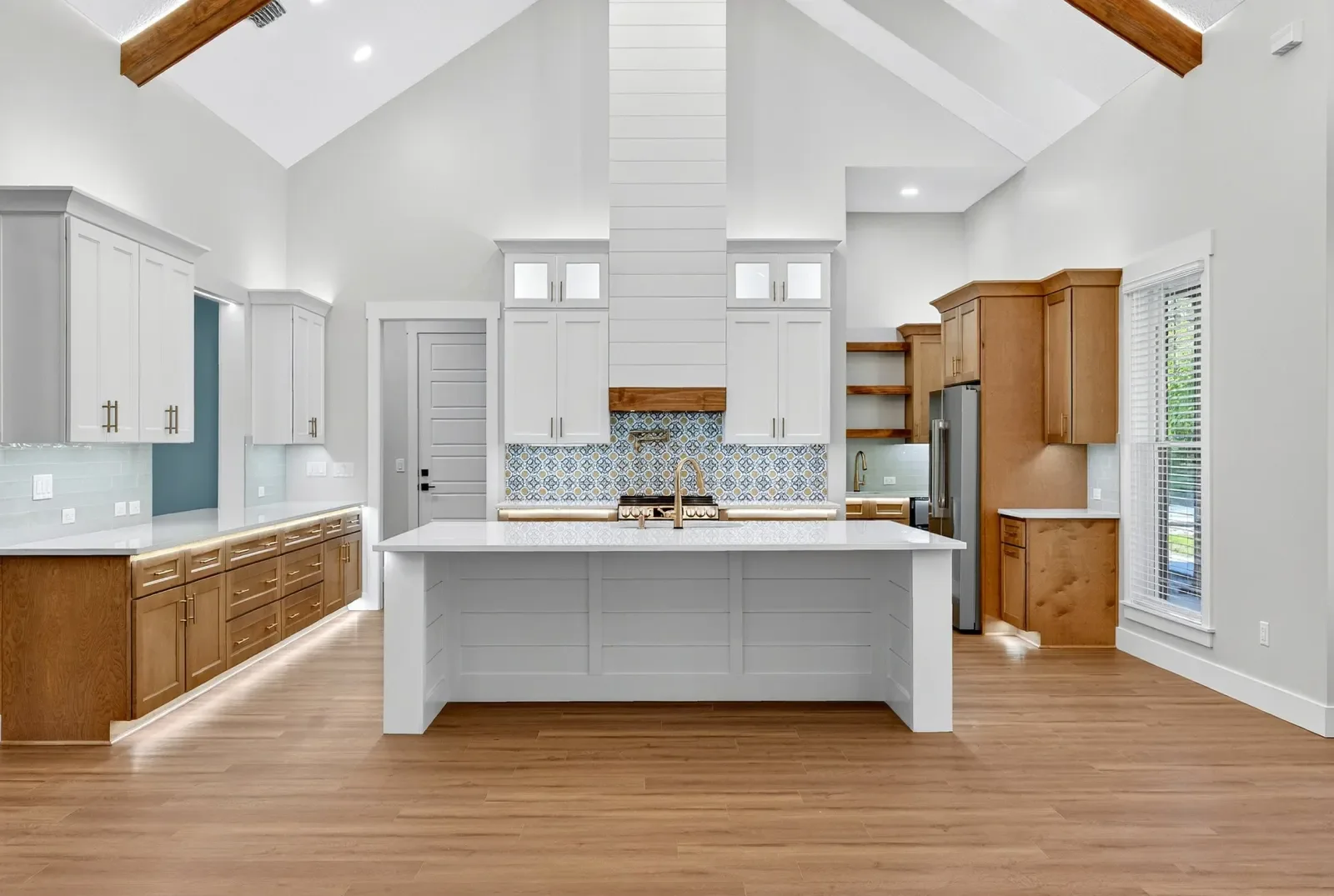 Vaulted kitchen with white island and patterned backsplash in North Florida. Real estate photography by Megapixeler