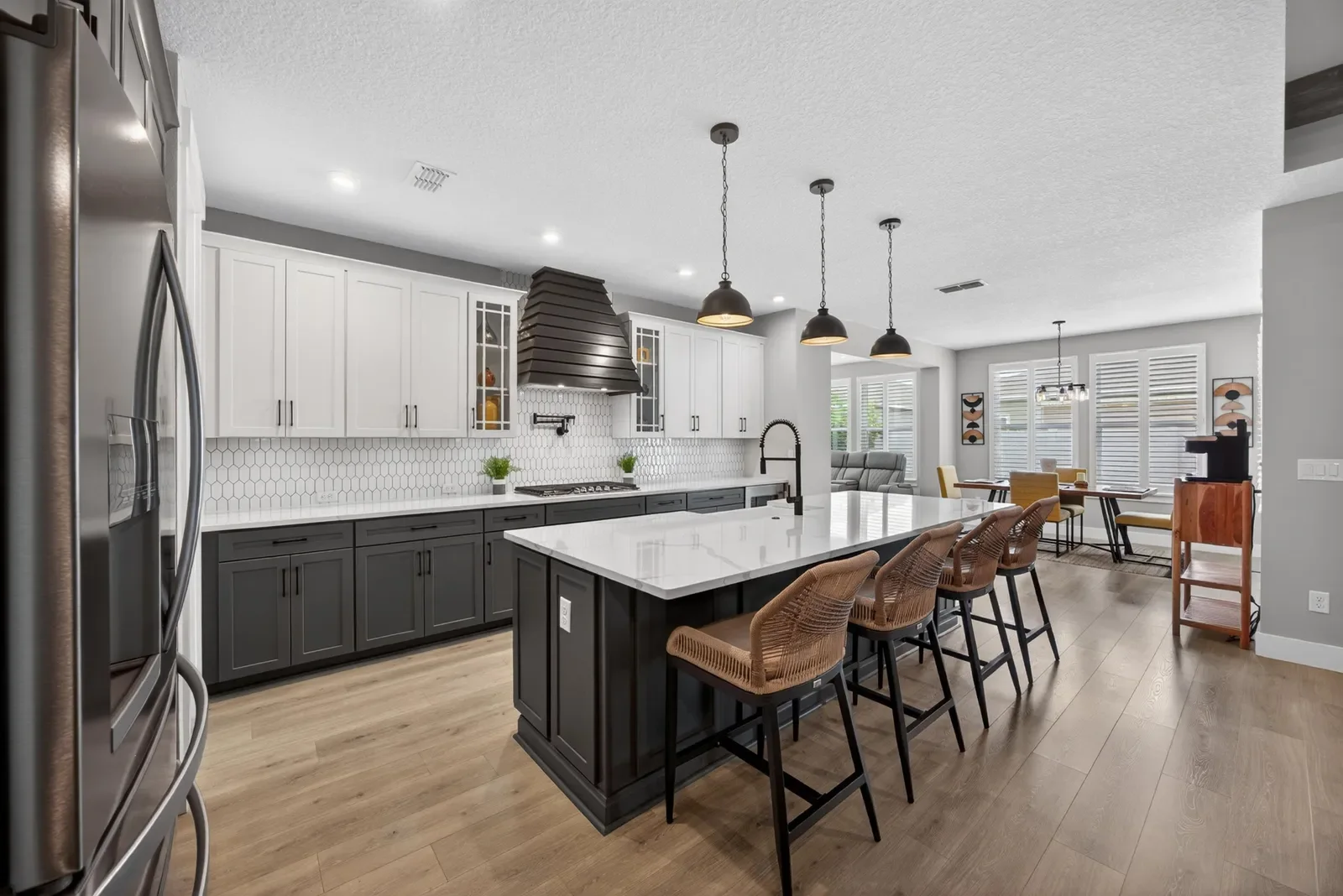 White kitchen with black island, quartz and leather bar stools in Middleburg, FL. Real estate photography by Megapixeler